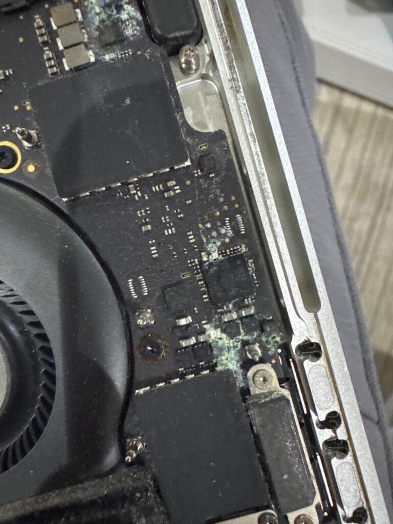 MacBook logic board with liquid damage corrosion under repair at Mak Doctor