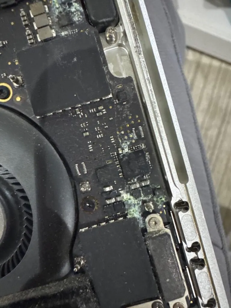 MacBook logic board with liquid damage corrosion under repair at Mak Doctor